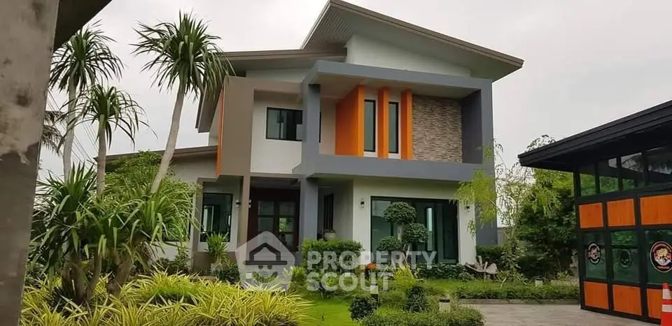Modern two-story house with vibrant orange accents and lush landscaped garden.