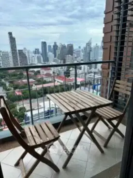 Stunning city view from a cozy balcony with wooden furniture, perfect for relaxation.