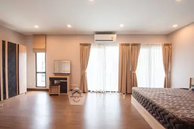 Spacious bedroom with wooden flooring and large windows for natural light