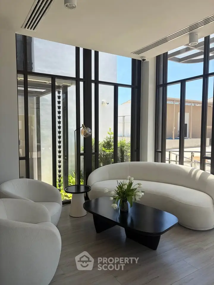 Elegant modern living room with large windows and stylish furniture, offering a bright and inviting atmosphere.