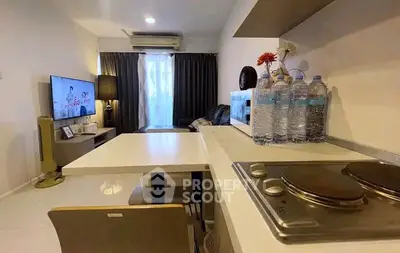 Modern open-layout living room with kitchen, featuring sleek furniture and cozy ambiance.