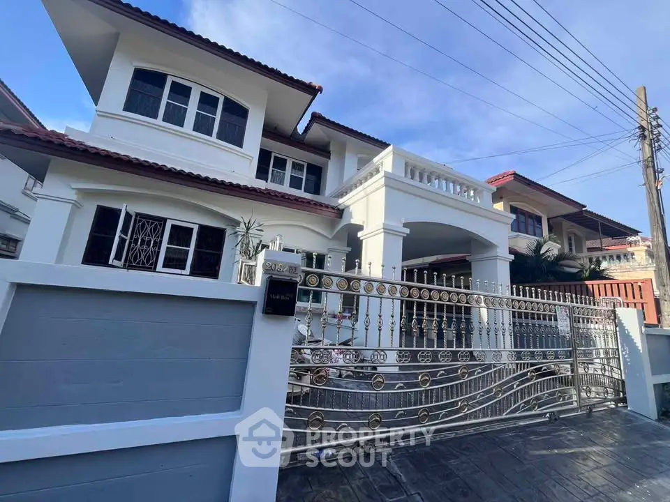 Elegant two-story house with ornate gate and spacious driveway in a serene neighborhood.