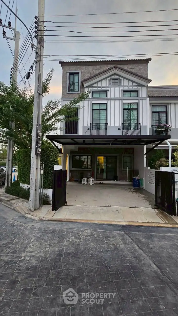 Modern townhouse exterior with driveway and balcony in a suburban neighborhood.