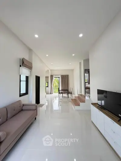 Spacious modern living room with sleek design and abundant natural light, featuring a cozy sofa and stylish TV unit.