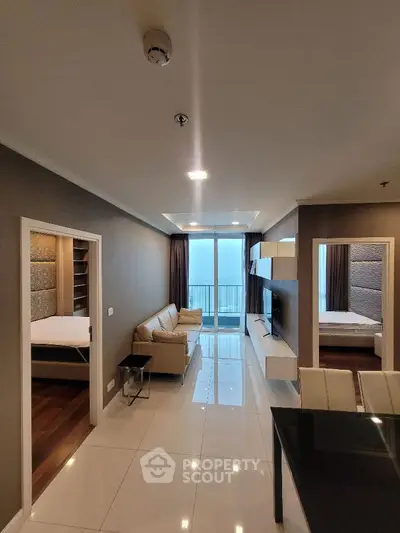 Modern apartment interior with sleek living room and two bedrooms, featuring glossy floors and a balcony view.