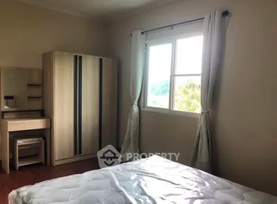 Cozy bedroom with natural light, featuring a wardrobe and dressing table, perfect for relaxation.