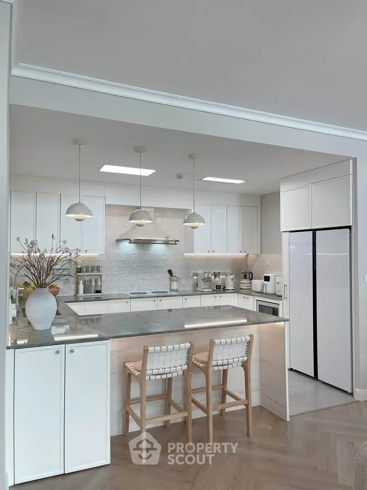 Modern kitchen with open layout, sleek white cabinets, and stylish bar seating