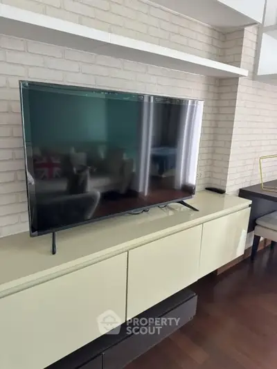 Modern living room with sleek TV setup and stylish brick accent wall.