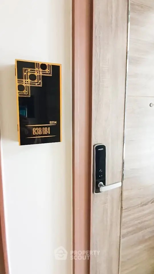 Modern apartment entrance with digital door lock and stylish room number plaque.