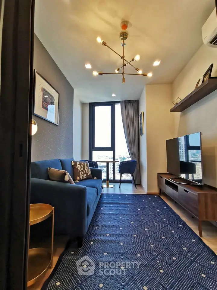 Modern living room with stylish decor, large window, and blue accents in a high-rise apartment.