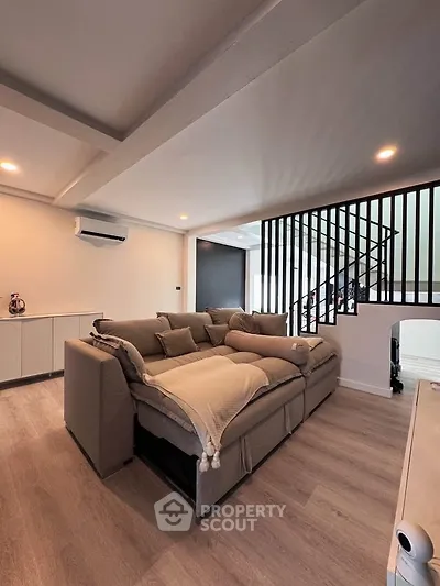 Spacious modern living room with cozy sectional sofa and stylish staircase