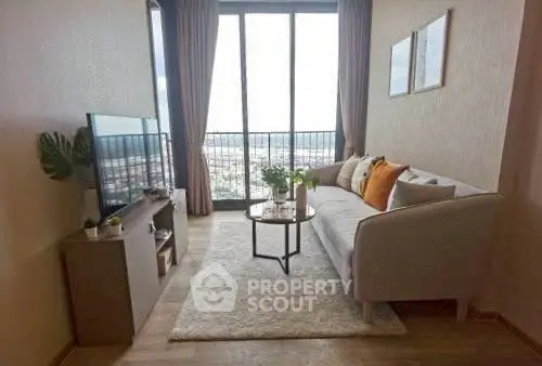 Modern living room with large window and cozy decor in high-rise apartment.