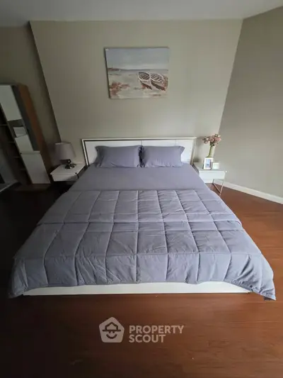Cozy bedroom with modern decor and wooden flooring, featuring a stylish bed and elegant side tables.