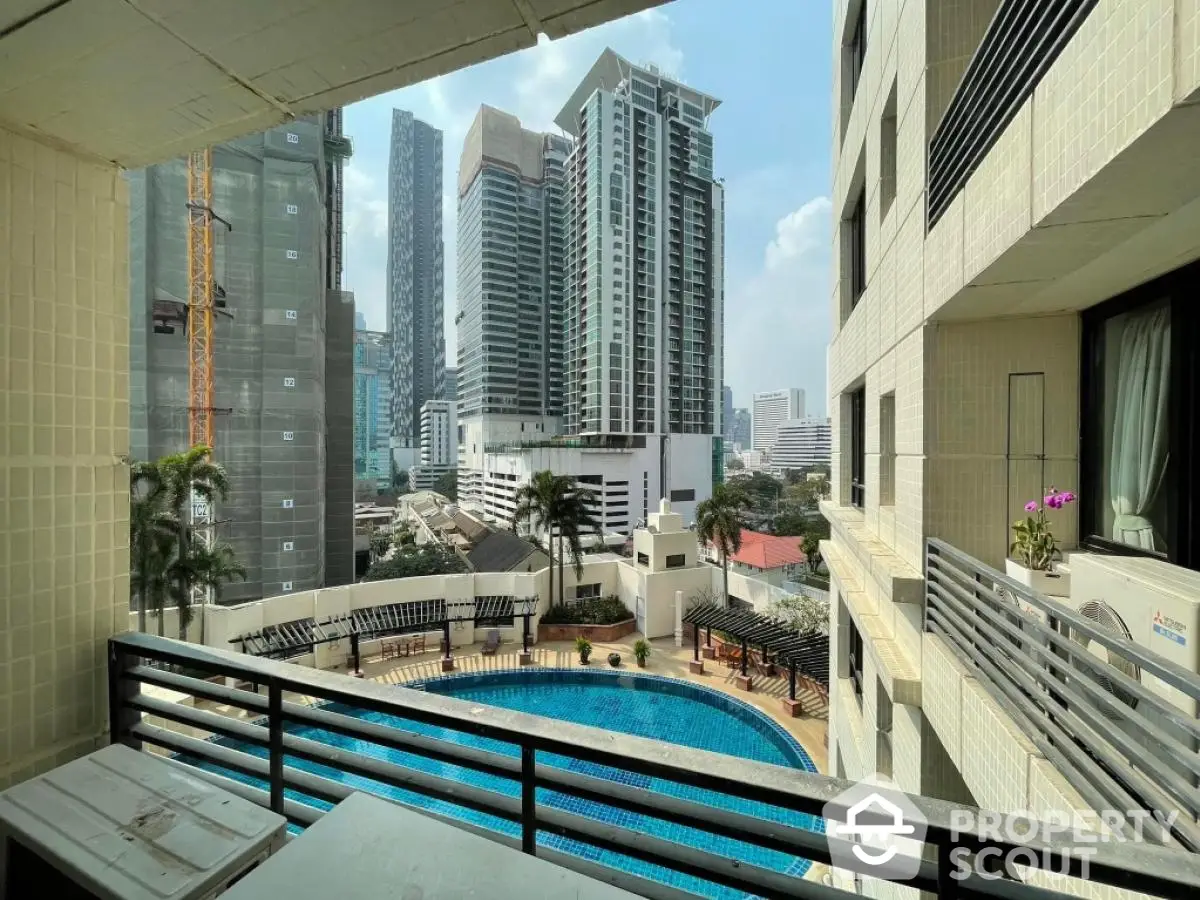 Stunning city view from a high-rise balcony overlooking a luxurious pool area.