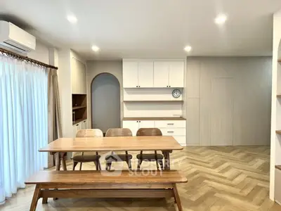 Modern dining area with wooden table and chairs, featuring stylish cabinetry and elegant lighting.