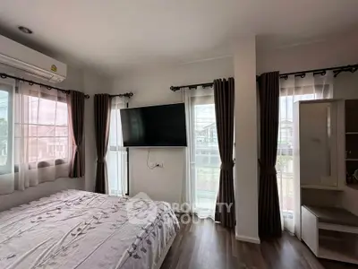 Bright bedroom with large windows, modern decor, and wall-mounted TV