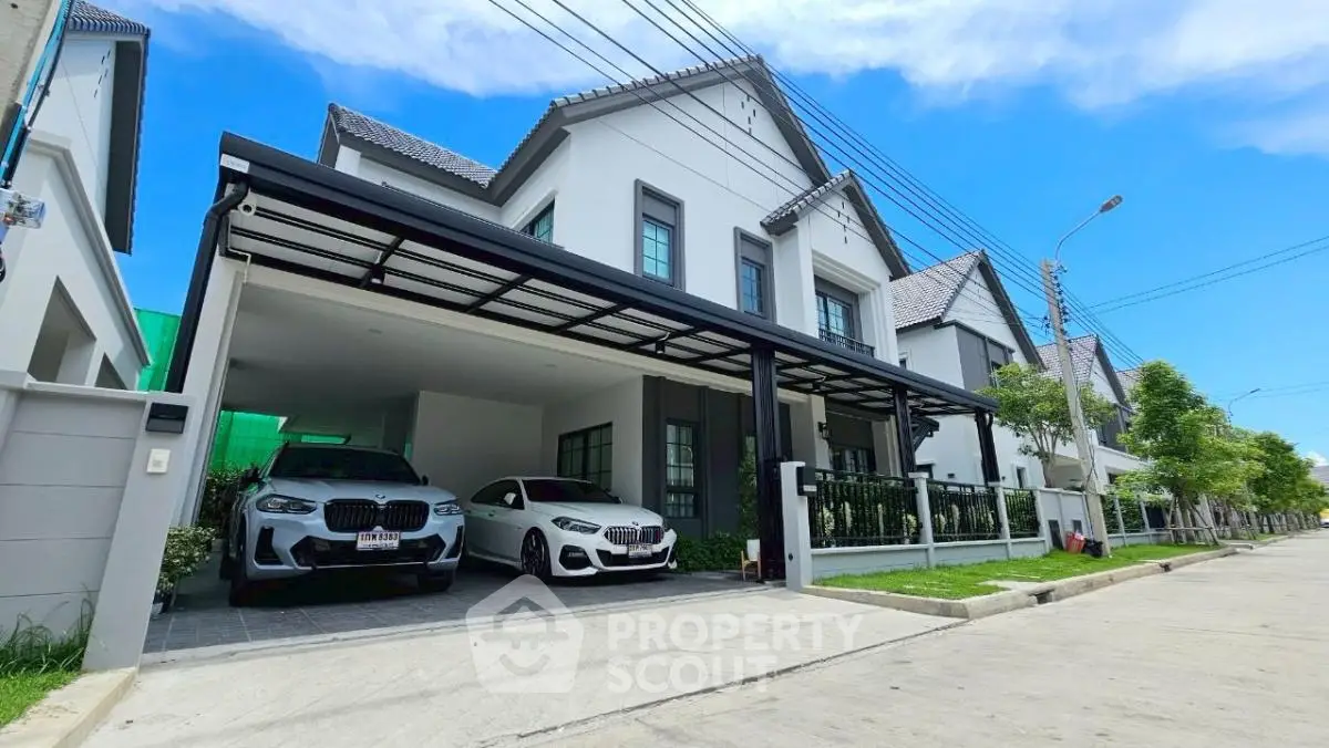 Modern suburban house with spacious driveway and two cars parked, showcasing contemporary architecture and lush surroundings.