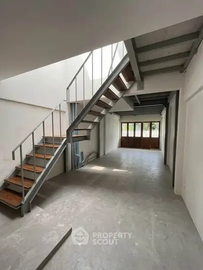 Spacious modern interior with open staircase and large windows, perfect for contemporary living.