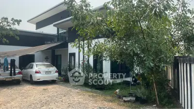 Modern two-story house with carport and lush garden in a serene neighborhood.
