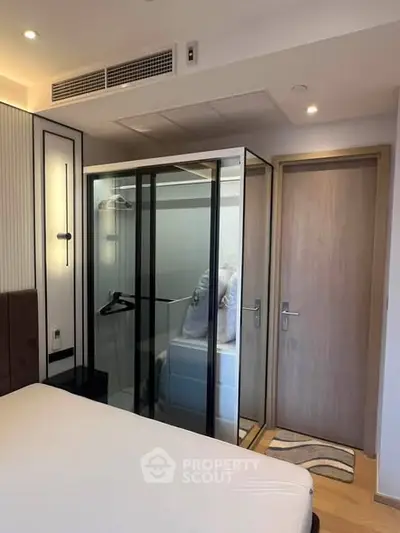 Modern bedroom with unique glass-enclosed wardrobe and minimalist design.