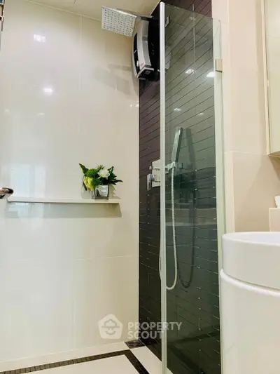 Modern bathroom with glass shower and sleek black tile accent wall