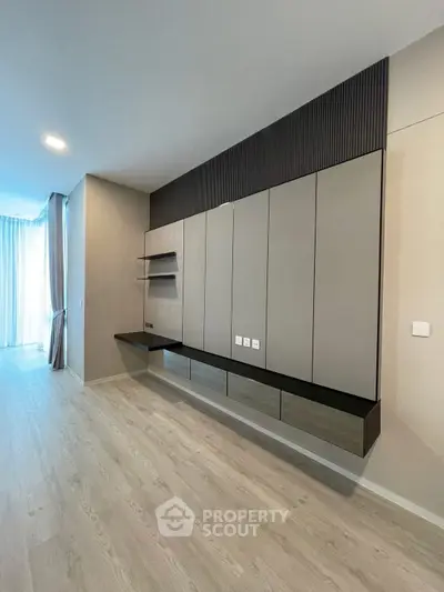 Modern minimalist living room with sleek built-in storage and light wood flooring.