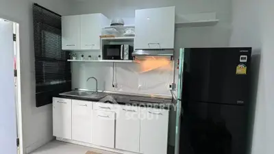 Modern kitchen with sleek white cabinets, black fridge, and built-in microwave in a compact layout.