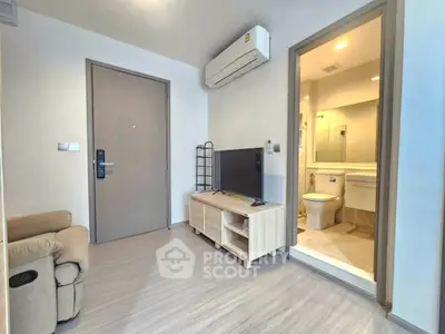 Modern living room with TV, air conditioning, and bathroom access in a cozy apartment.