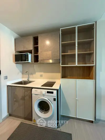 Modern compact kitchen with washing machine and microwave, sleek cabinets, and efficient layout.