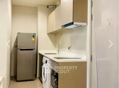 Compact kitchen with modern appliances including fridge and washing machine, ideal for urban living.