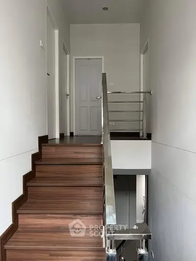 Modern staircase with wooden steps and sleek metal railing in a contemporary home