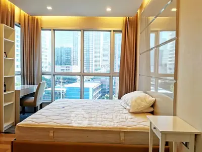 Bright bedroom with large windows offering stunning city views in a modern apartment.