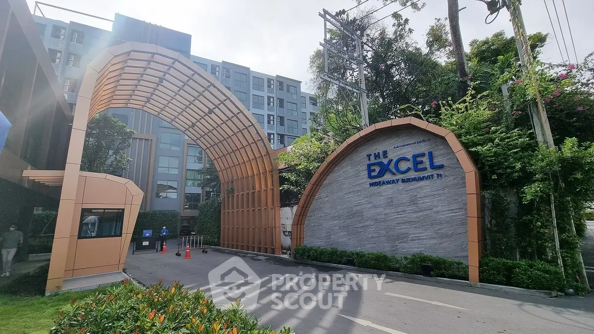 Modern apartment building entrance with unique architectural design and lush greenery.