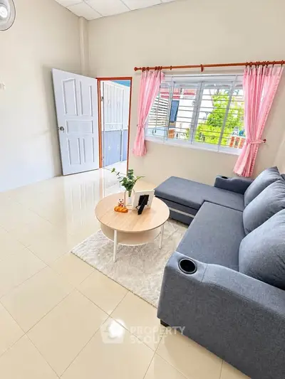 Bright living room with modern gray sofa and natural light through large window.