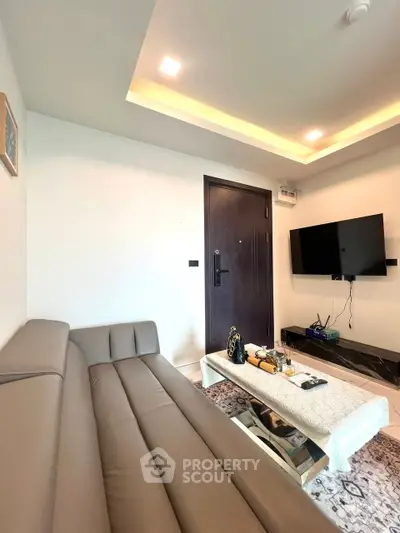 Modern living room with sleek sofa, wall-mounted TV, and stylish lighting.