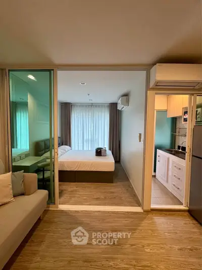 Modern studio apartment with open layout, featuring a cozy living area and a compact kitchen.