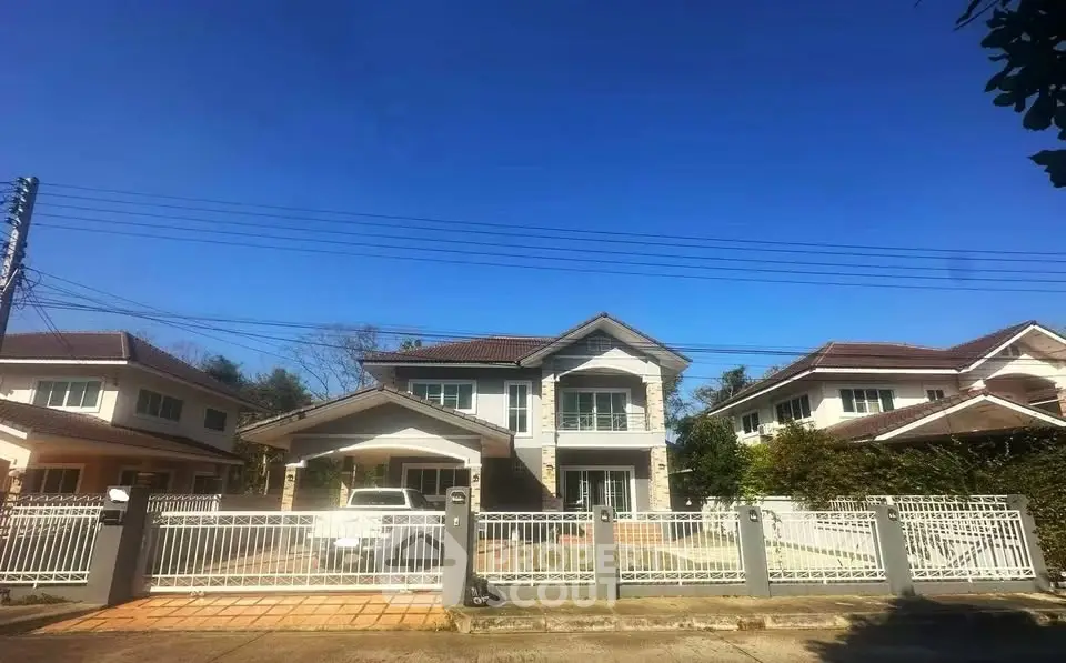 Charming suburban house with gated driveway and clear blue sky