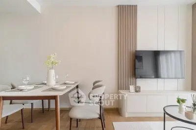 Modern living room with elegant dining area and wall-mounted TV, featuring minimalist decor and wooden flooring.