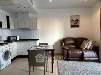 Modern living room with open kitchen, featuring leather sofa and dining area