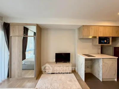Modern studio apartment with open kitchen and cozy living area, featuring sleek wooden cabinetry and natural light.