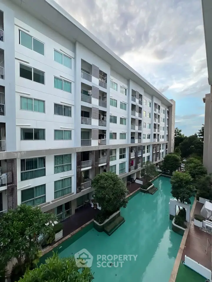 Modern apartment building with pool view and lush greenery, perfect for urban living.