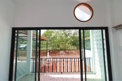 Spacious balcony with sliding glass doors and scenic view of lush greenery.