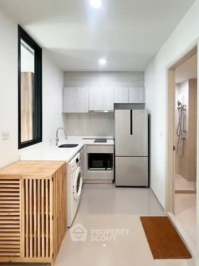 Modern kitchen with sleek appliances and washing machine in compact layout