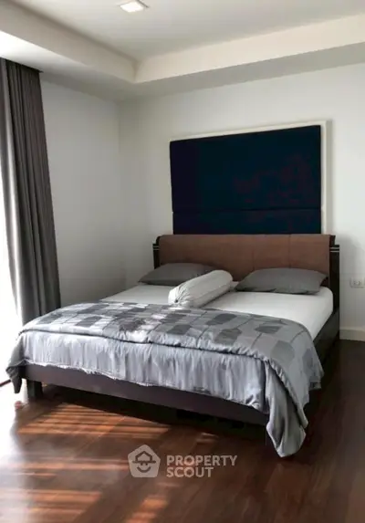 Spacious bedroom with modern decor and large window for natural light.