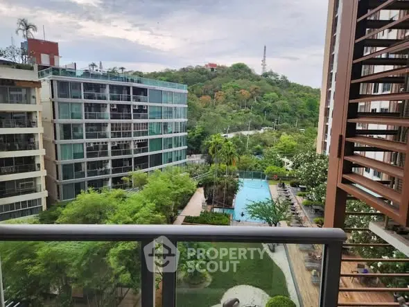 Stunning balcony view of lush greenery and modern apartment complex with pool.