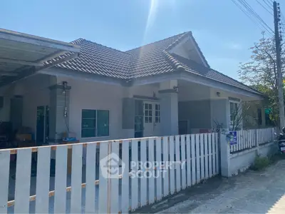 Charming single-story house with tiled roof and white picket fence in a sunny neighborhood.