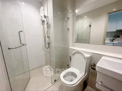 Modern bathroom with glass shower and sleek fixtures in contemporary apartment.