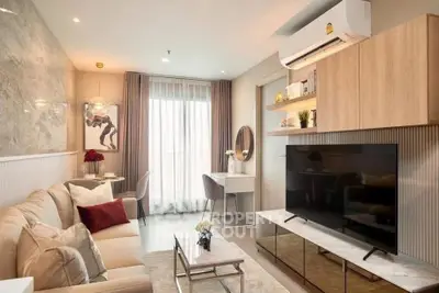 Modern living room with stylish decor and large TV, featuring elegant furniture and natural light.