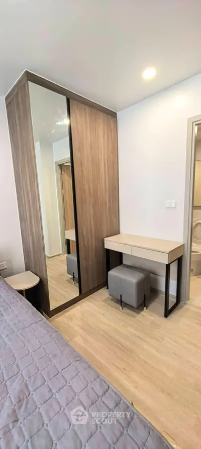 Modern bedroom with mirrored wardrobe and stylish vanity in a cozy apartment.