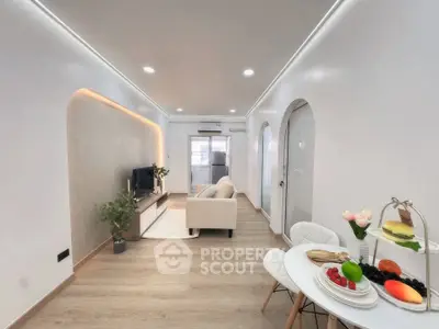 Modern living room with stylish decor and open dining area, featuring sleek furniture and ambient lighting.